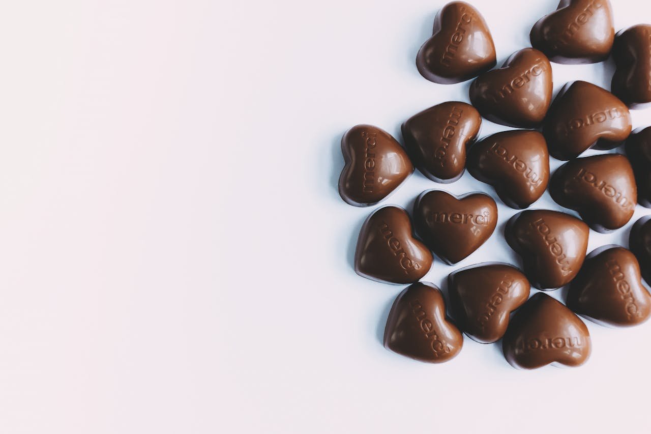 Flat lay of heart-shaped milk chocolates with merci text, perfect for gifting.